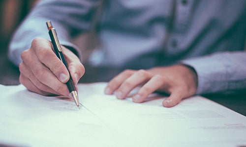 A man signs a piece of paper.