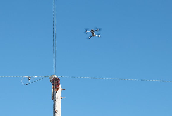 A drone hovers above an electrical pole