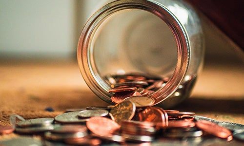 A jar of coins spills out on a table